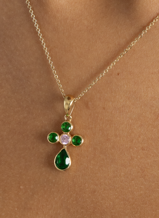 Close-up of the Bendita pendant in gold vermeil with green and pink stones, styled on a model’s neckline.

Collar Bendita en oro vermeil con piedras verdes y rosa, mostrado en el escote de la modelo.