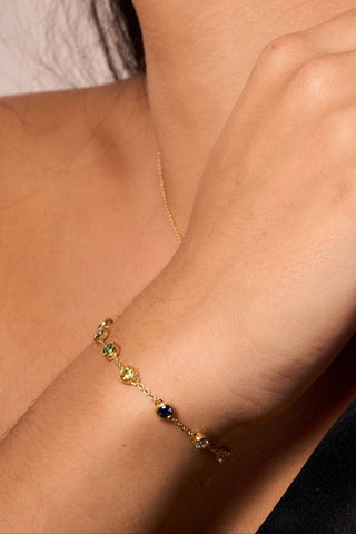 Gold Alba bracelet with colorful gemstones, styled alongside a black outfit and matching gold ring.

Pulsera Alba dorada con gemas de colores, combinada con un atuendo negro y un anillo dorado a juego.