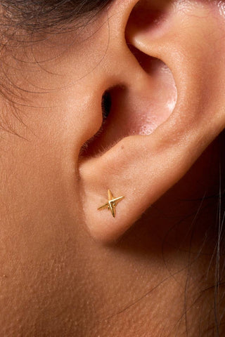 Gold star-shaped earring on a person's ear