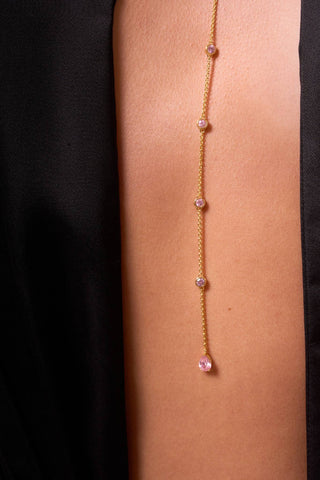 Close-up of Luzia Y-chain pink stones against skin.

Primer plano de la cadena en Y del collar Luzia con piedras rosas sobre la piel.