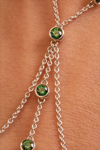 Close-up of green bezel-set stone detail on Solaris hand chain in sterling silver.

Detalle en primer plano de piedra verde engastada en bisel en la pulsera Solaris de plata esterlina.